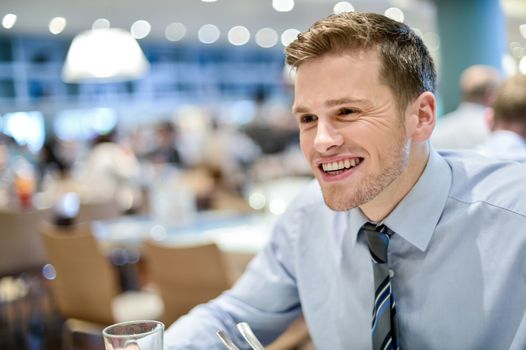 Relaxed smiling corporate male sitting in restaurant