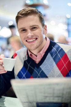 Young man posing at cafe with coffee cup