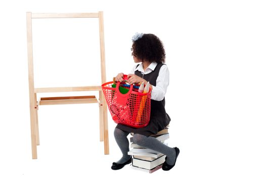 School girl sitting on books, watching the board