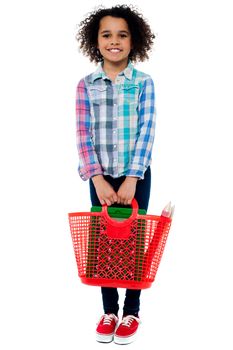 Little girl standing with basket bag over white