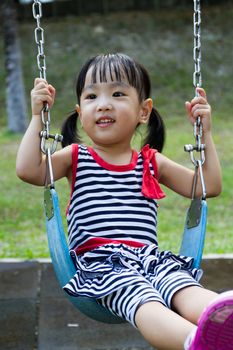 Asian Chinese little girl swing at outdoor park.