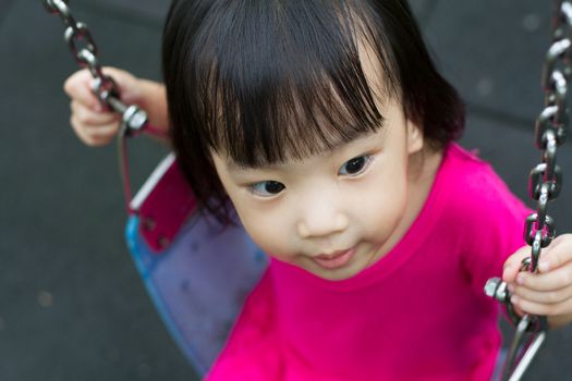Asian Chinese little girl swing at outdoor park.