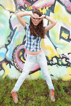 Portrait of young woman sitting at graffiti wall