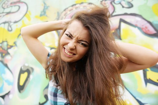 Portrait of young woman sitting at graffiti wall