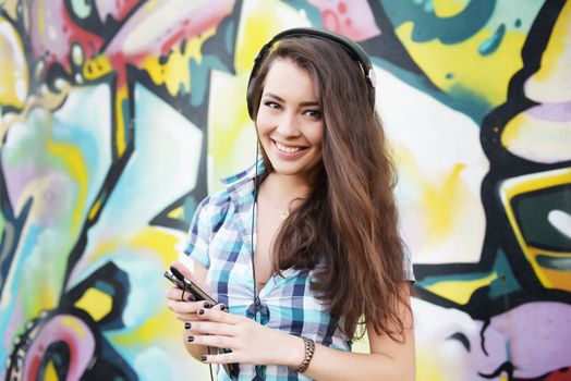 Portrait of young woman sitting at graffiti wall