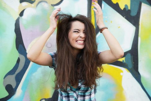 Portrait of young woman sitting at graffiti wall