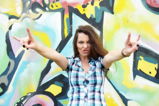 Portrait of young woman sitting at graffiti wall