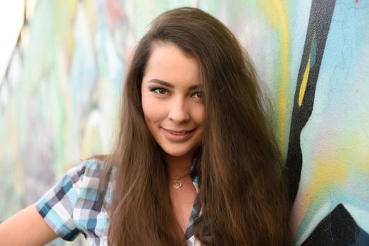 Portrait of young woman sitting at graffiti wall