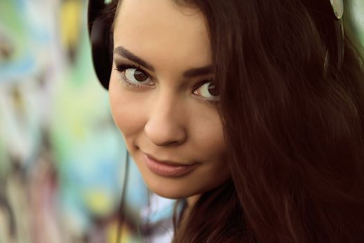 Portrait of young woman sitting at graffiti wall