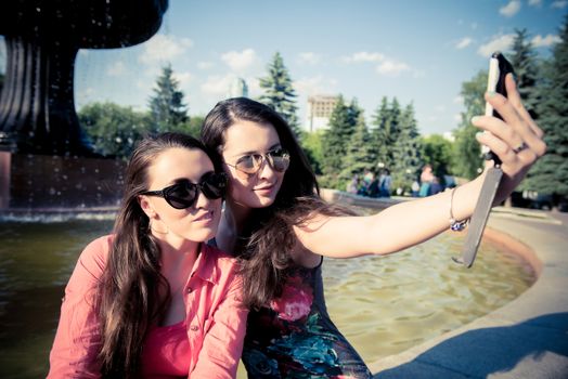 Two young women taking a selfie outdoors in summer