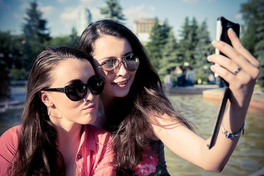 Two young women taking a selfie outdoors in summer