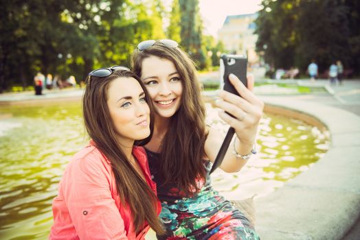 Two young women taking a selfie outdoors in summer