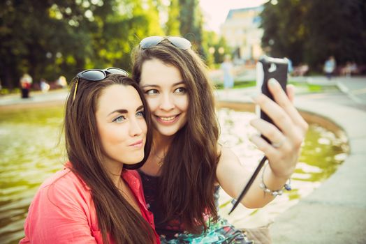 Two young women taking a selfie outdoors in summer