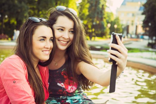 Two young women taking a selfie outdoors in summer