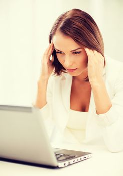 business, stress and technology concept - businesswoman with laptop in office