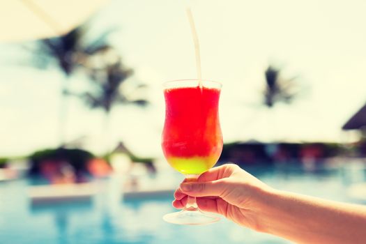 vacation, beverage and travel concept - close-up of female hand holding glass with cocktail