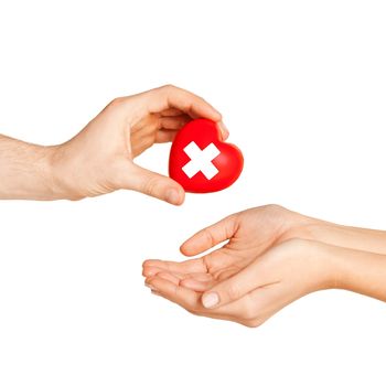 healthcare, charity and medicine concept - doctor hand giving heart with red cross symbol to patient