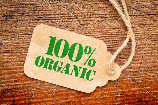 one hundred percent organic sign - a paper price tag against rustic red painted barn wood - shopping concept