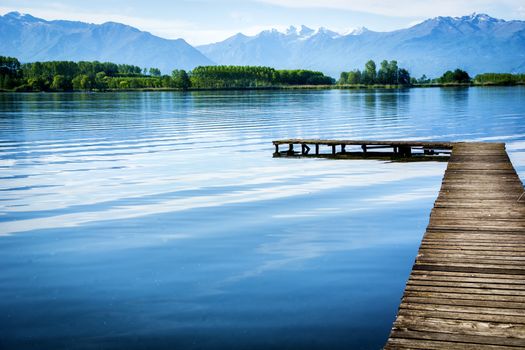 Wooden small pier over peaceful lake. Daytime shot