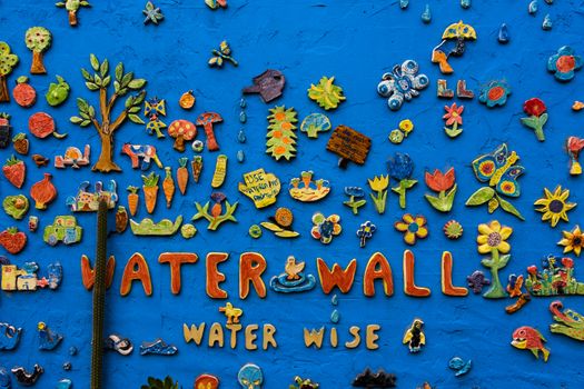 Found in a community garden in St Kilda Melbourne, a brightly coloured wall with colourful artwork of fish, flowers, animals and objects.