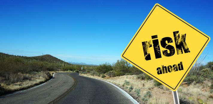 Risk ahead sign on a sky background and dessert road