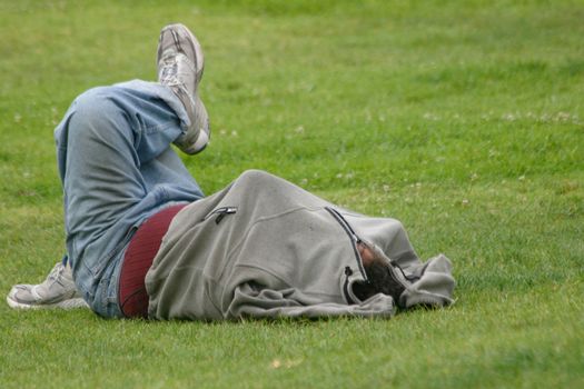 A Homeless man is sleeping on the grass in the Park. Los Angeles in California, USA