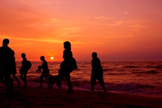 Vacation conceptual image. Family walking on the beach at sundown.