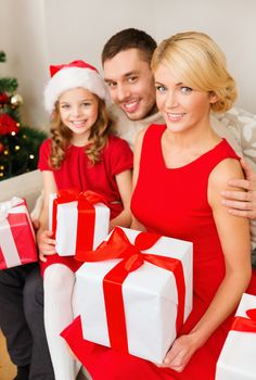 family, christmas, x-mas, happiness and people concept - smiling family in santa helper hats with many gift boxes
