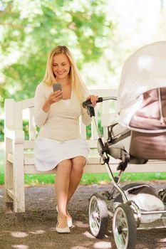 family, parenthood, technology and people concept - happy mother with with smartphone and baby stroller in park