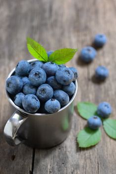 Metal cup and Blueberry on old wood