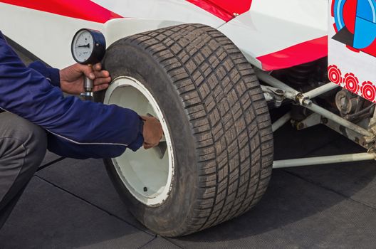 Checking the rear wheel of a racing car before the test drive.