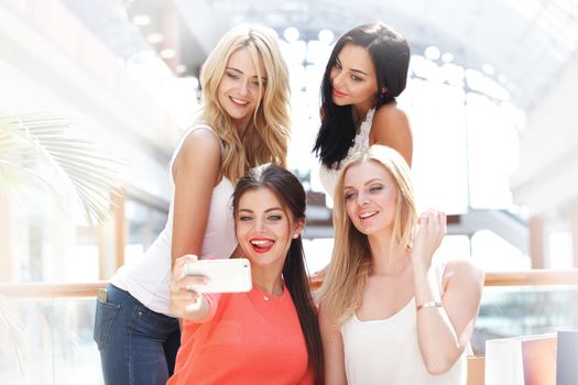 Happy female friends taking selfie in shopping mall