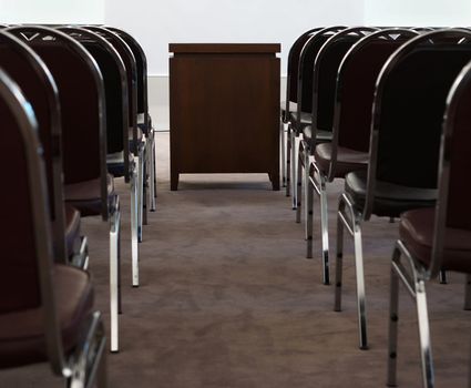 Inside meeting room at office, have many chairs and table for a slide projector in the middle.                       