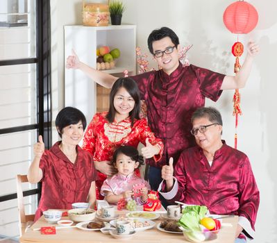 Chinese New Year, reunion dinner. Happy Asian Chinese multi generation family with red cheongsam dining at home.