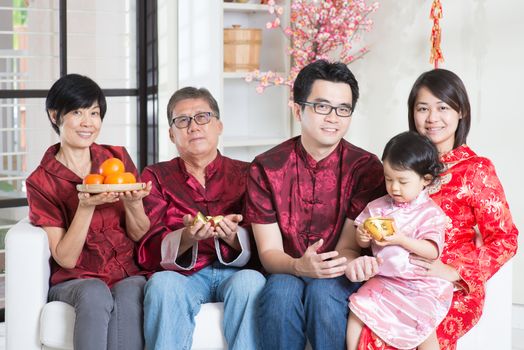 Celebrating Chinese new year. Happy Asian multi generations family in red cheongsam reunion at home.