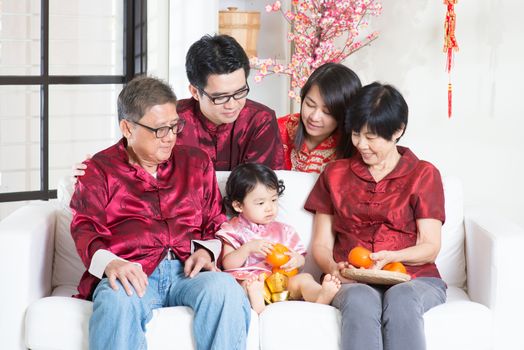 Chinese new year festival. Happy Asian multi generations family in red cheongsam reunion at home.