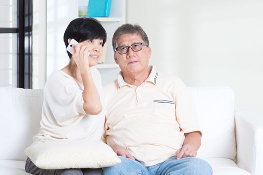 Asian senior couple calling on phone, using smartphone. Family living lifestyle at home.