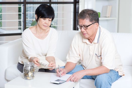 Asian senior couple counting on money. Saving, retirement, retirees financial planning concept. Family living lifestyle at home.