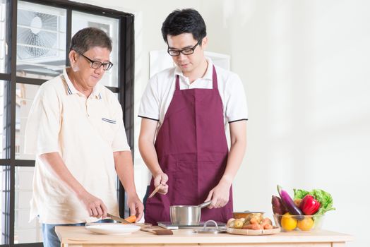 Asian senior father and adult son cooking meal at kitchen. Family living lifestyle at home.