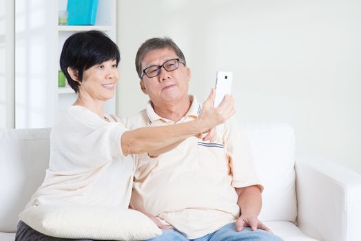 Modern technology, age and people concept. Asian senior couple selfie, using smartphone, self photographing. Family living lifestyle at home.