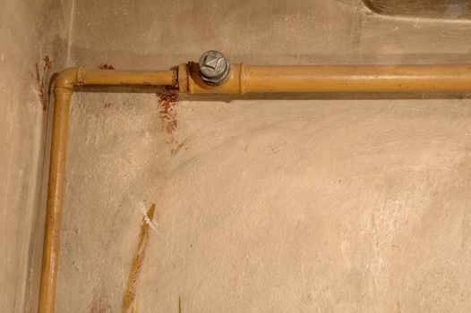 Old yellow pipe and dirty wall in old boiler room