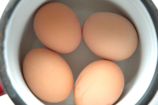 Four eggs inside small, round pot