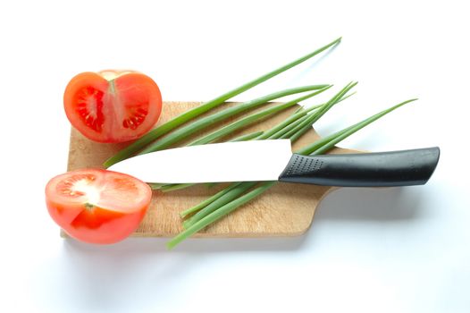 Vegetables and knife on chopping board on white background