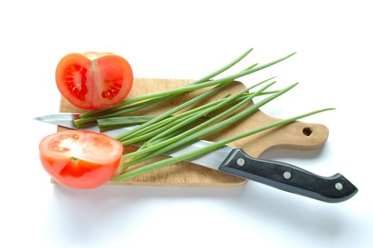 Vegetables and knife on chopping board on white background