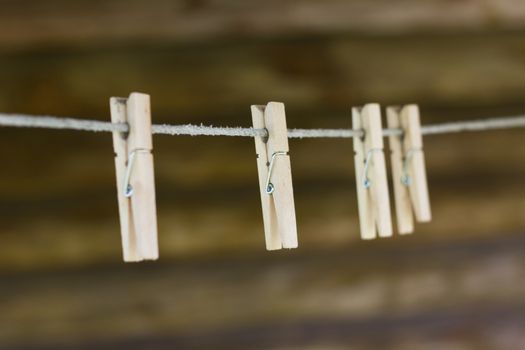 Wooden clothespins on the clothesline. On the background of old wooden house