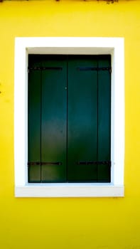 green wood paint Window in Burano with bright yellow wall building architecture, Venice, Italy