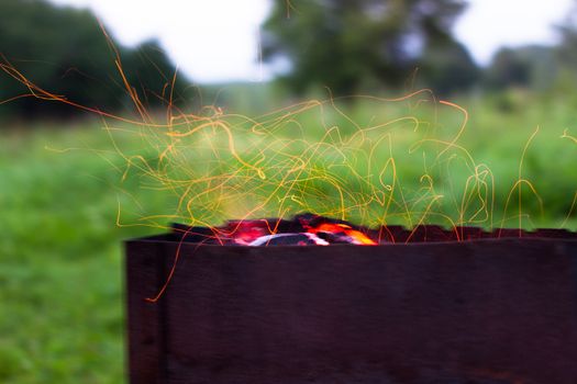 barbecue sparks fly from the barbecue evening dinner cooking coals of fire