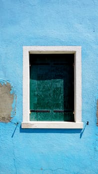Window in Burano on blue decay wall building architecture, Venice, Italy