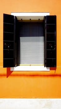 Window in Burano on orange wall building architecture, Venice, Italy