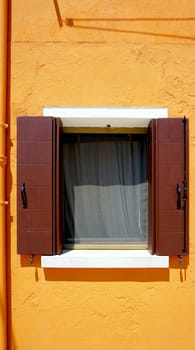 Window in Burano on orange wall building architecture, Venice, Italy